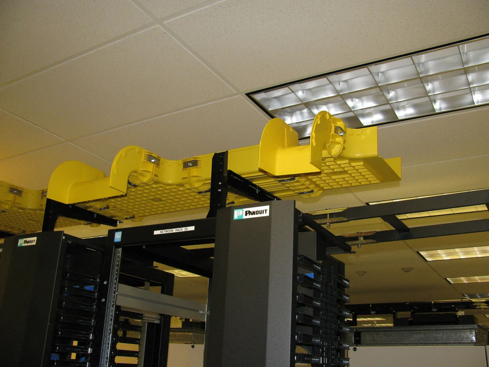 Bundles of yellow fibre optic patch cables routed through cable management on a network rack